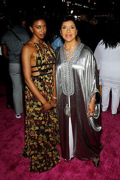 two women standing next to each other on a pink carpet