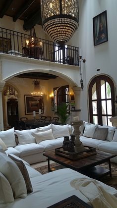 a living room filled with lots of furniture and a chandelier hanging from the ceiling