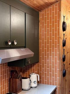 a kitchen with green cabinets and white counter tops next to a wall mounted range hood