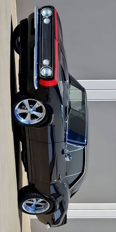 the front end of a black car with chrome rims and wheels is shown from above