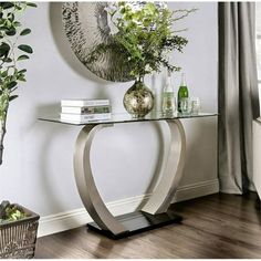 a console table with glass top and metal base in front of a wall mounted clock