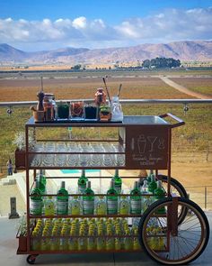 a cart with drinks on it sitting in front of a field