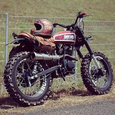 a dirt bike parked next to a fence on the side of a road in front of a field