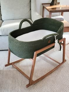 a wicker bassinet on a wooden stand in front of a couch