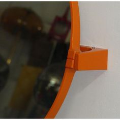 an orange mirror mounted to the side of a white wall