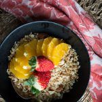 a black bowl filled with oatmeal and fruit on top of a table