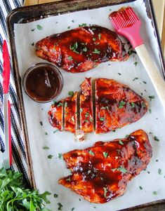 bbq chicken wings with barbecue sauce and garnishes on a baking sheet