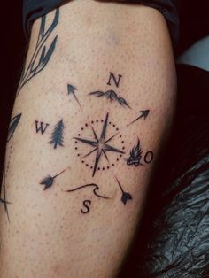 a woman's thigh with an arrow and compass tattoo on it