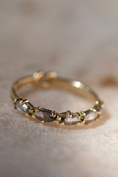 a close up of a gold ring with three stones on it's side, sitting on a marble surface