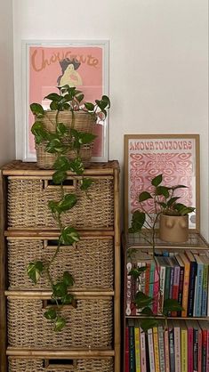 there is a plant on top of a wicker dresser next to books and magazines