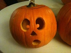 two carved pumpkins sitting on top of a white plate next to each other with holes in them