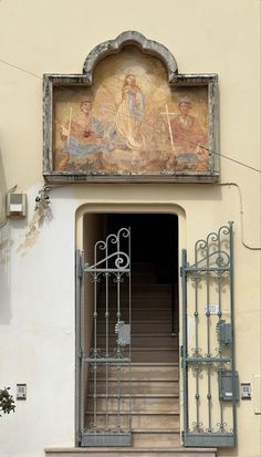 an entrance to a building with a painting on the wall and stairs leading up to it