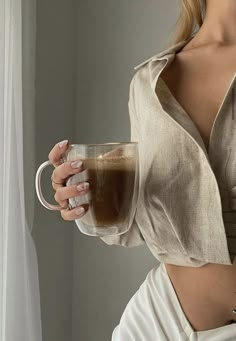 a woman holding a coffee cup in her right hand and wearing a white skirt on the other side