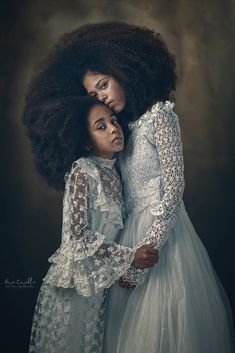 two women in white dresses hugging each other