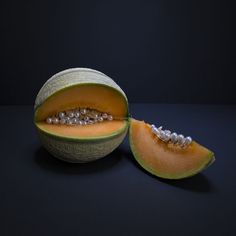 a cantaloupe is cut in half on a black surface with beads around it