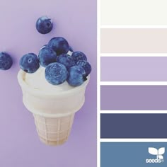 an ice cream cone with blueberries on top and the color scheme is purple, white, and grey