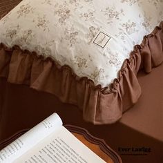 an open book sitting on top of a bed next to a pillow