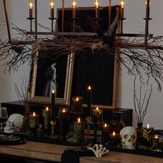 a table topped with candles and skulls in front of a framed photo on the wall