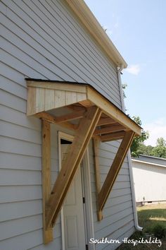 an upside down window on the side of a white house with wood trimmings