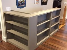 an empty book shelf in the corner of a room with pictures on the wall behind it