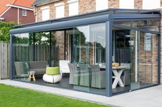 a patio covered in glass and furniture next to a brick building