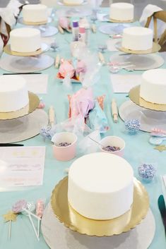 a table topped with lots of white cake covered in frosting next to other plates