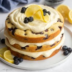 a stack of lemon blueberry cake on a white plate with sliced lemons and blueberries