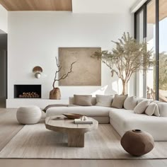 a modern living room with white furniture and large windows overlooking the trees in the distance