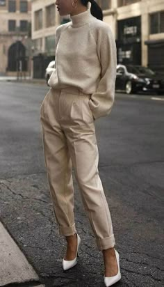 a woman standing on the side of a road wearing high heels and a turtle neck sweater