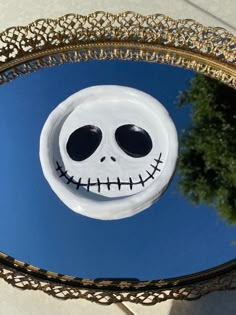 a mirror with a jack skellingy face in the middle and a tree behind it