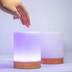 a person reaching for something on top of a wooden stand next to a white light