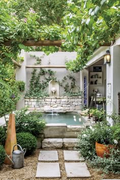 an outdoor garden with a fountain surrounded by greenery and potted plants on either side