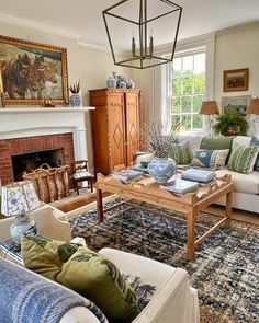 a living room filled with furniture and a fire place under a chandelier in front of a window