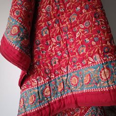 the back of a red and blue dress with floral designs on it's sleeves