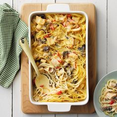 a casserole dish with chicken, mushrooms and pasta on a wooden cutting board