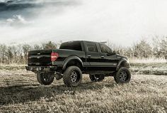 a black pickup truck parked in a field