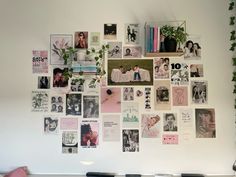 a white wall with many pictures and plants on it