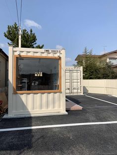 a small white container sitting in the middle of a parking lot next to a building