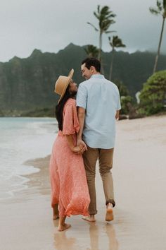 a man and woman walking on the beach with palm trees in the backgroud