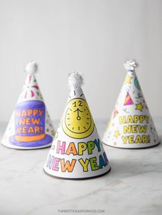 three party hats with the words happy new year written on them, all in different colors