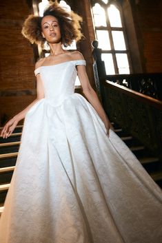 a woman in a white dress standing on some stairs