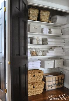 an organized pantry with white linens and baskets