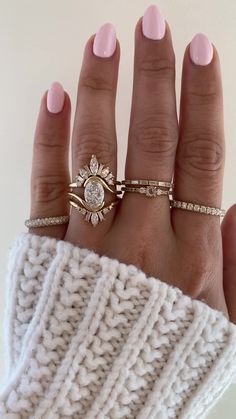 a woman's hand with three different rings on her fingers and one is wearing a sweater