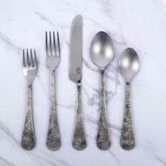 five silverware with spoons, forks and knives on a white marble countertop