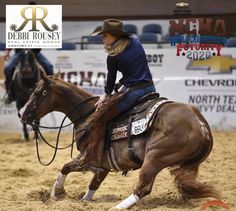 a woman riding on the back of a brown horse in a dirt field at a rodeo