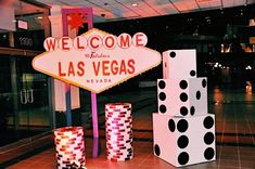 the las vegas sign is lit up in pink and black polka dots, with dices stacked next to it