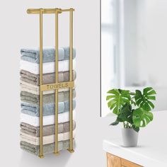 a towel rack with towels on it next to a potted plant