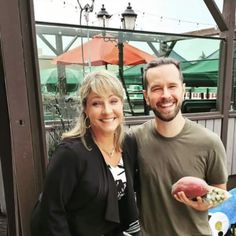 a man and woman standing next to each other holding a football