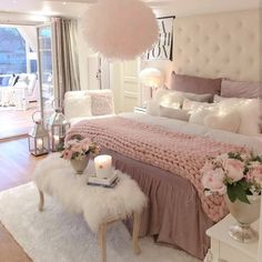 a bedroom decorated in pink and white with flowers on the bed, lights hanging from the ceiling