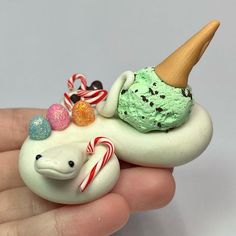 an ice cream sundae with candy canes and candies on it in someone's hand